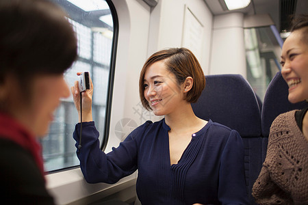 年轻女子与朋友在火车窗口拍照图片