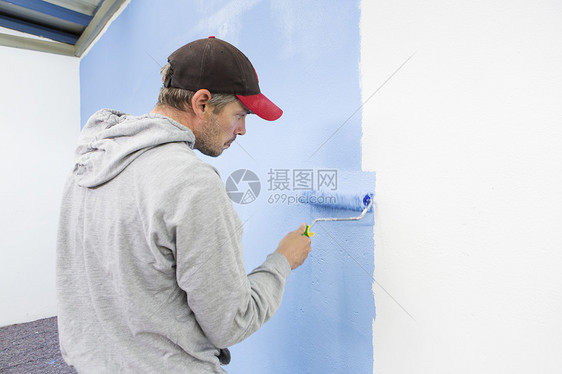 在墙上刷漆的工人图片