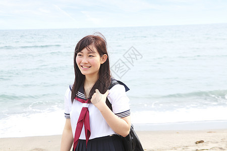 身着校服站在沙滩上的年轻女子图片