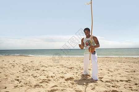 海滩上拿着棍子的男人图片