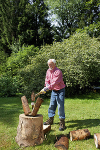 高年男子在花园里砍伐原木图片