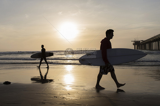 两个男人拿着冲浪板在海滩上 图片