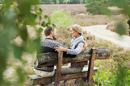 成人夫妇坐在户外木椅上交谈图片