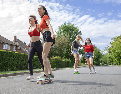 4名在路上玩滑板的年轻女子图片