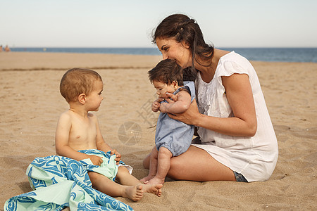 母亲和婴儿坐在沙滩上图片