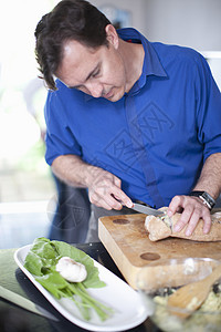 男子在切菜板上切面包图片