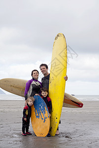 在海滩上拿着冲浪板的一家人图片