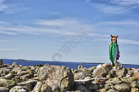 身着绿色斗篷的男孩站在石墙上图片