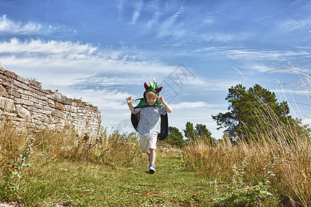 男孩穿着绿色斗篷在草地上跑动图片