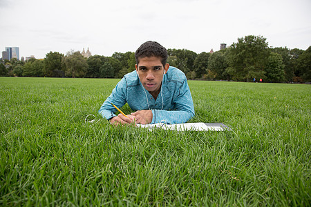 躺在草地上做功课的年轻人图片