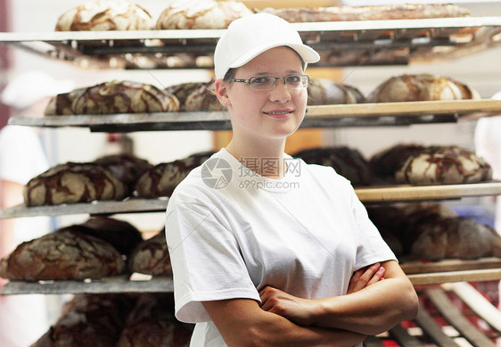 面包师抱臂站在面包架前微笑图片