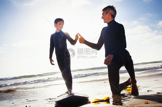 海滩上教儿子使用冲浪板的父亲图片
