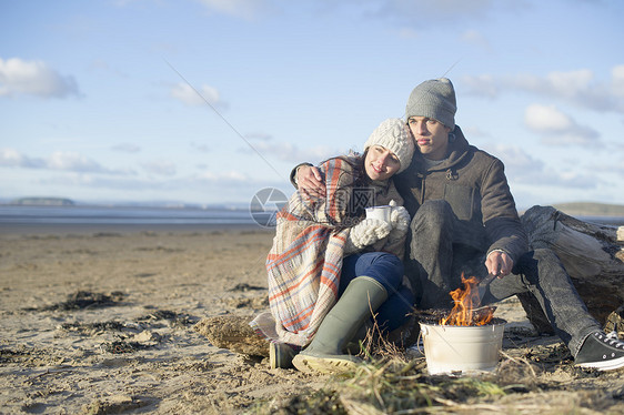 英国布赖恩沙地萨默塞特的沙滩上情侣抱在一起烤火图片