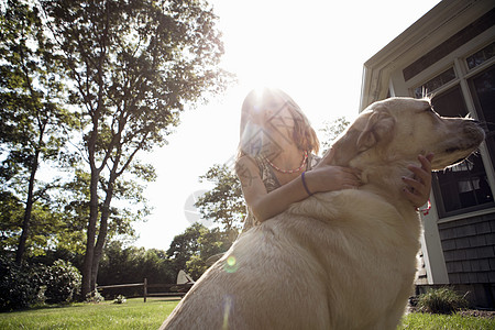 在花园里拥抱宠物狗狗的年轻女孩图片