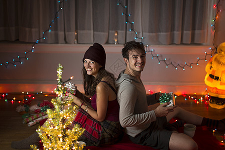 年轻夫妇圣诞节在客厅交换礼物图片