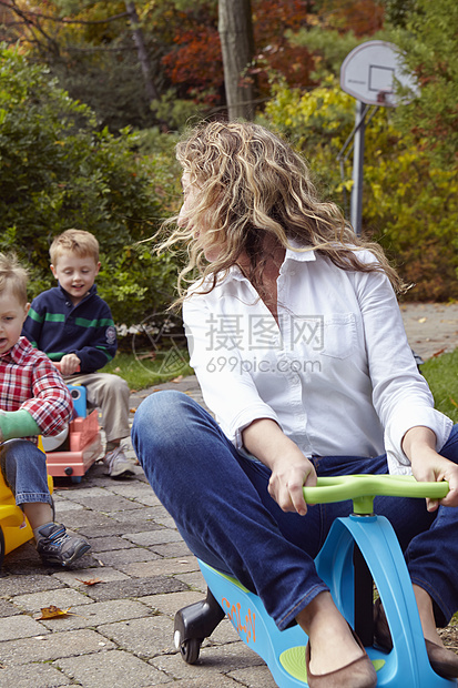 母亲和年轻儿子在花园里玩玩具车图片