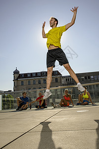 年轻男教练在城市屋顶上热身运动图片