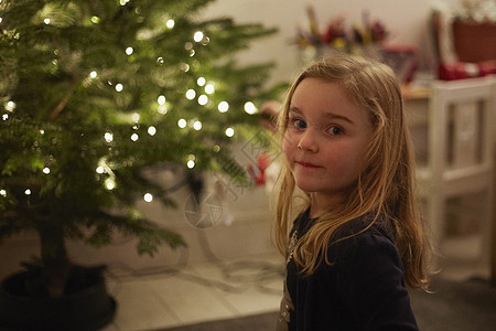 年幼女孩站在圣诞树前图片