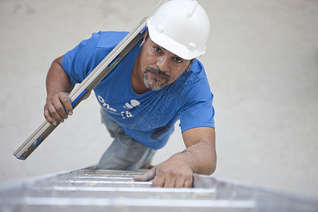 带着金属材料攀爬梯的建筑工图片