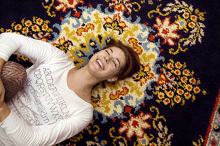 年轻女人躺在复古地毯上笑着图片
