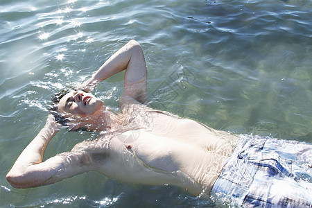 年轻人双手放在头后漂浮在水中图片