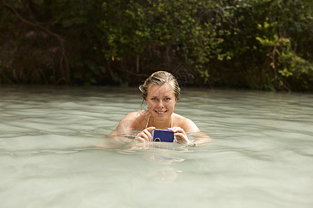 在岩石池的年轻女子拿着水下摄像机图片