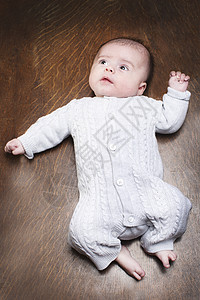12个月婴儿男孩躺在木地板上图片