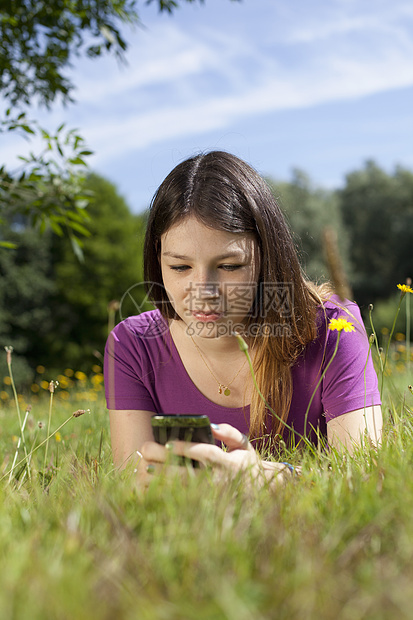 少女躺在公园里看着手机图片