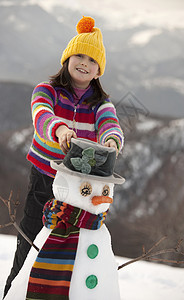 少女在雪人身上戴帽子图片