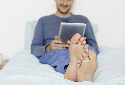 成人中年男子用数字平板电脑躺在床上图片