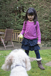 女孩和宠狗在花园里玩球图片