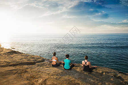 坐在悬崖顶上看着海和冥想的女人图片
