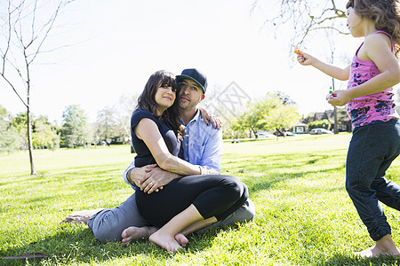 与年轻女儿一起坐在公园的成年中夫妇图片