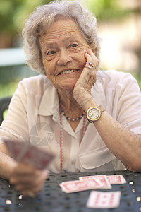 在花园桌上打牌的年长妇女图片