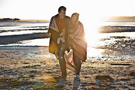 在沙滩上散步的一对夫妇裹在毯子里的一对夫妇图片