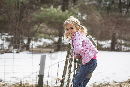 女孩在野外攀爬铁丝网围栏图片