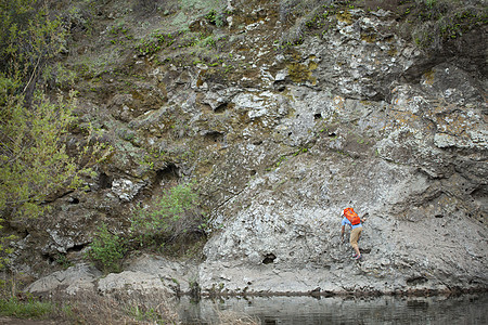 美国加利福尼亚州马里布溪立公园湖边岩石上攀登的年轻人图片