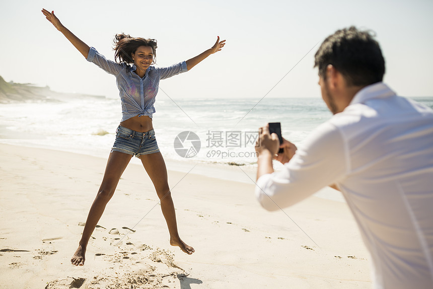 巴西里约热内卢阿波多尔海滩中年男子拍摄女友跳跃图片