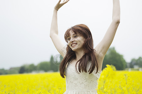 在油菜花田里举起双臂的年轻女子图片