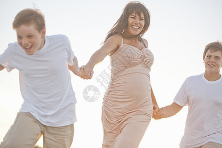 假期母亲和两个儿子在户外手牵手跑步图片