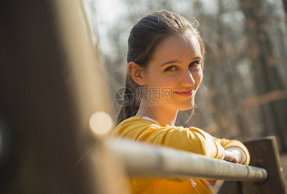 倚在森林围栏上的年轻女人图片