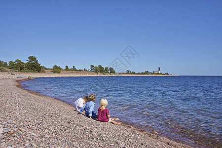 三个孩子坐在沙滩上图片