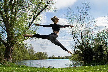 年轻舞者在湖边中空跳跃图片