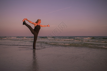日落时在海滩上做瑜伽姿势的成人图片
