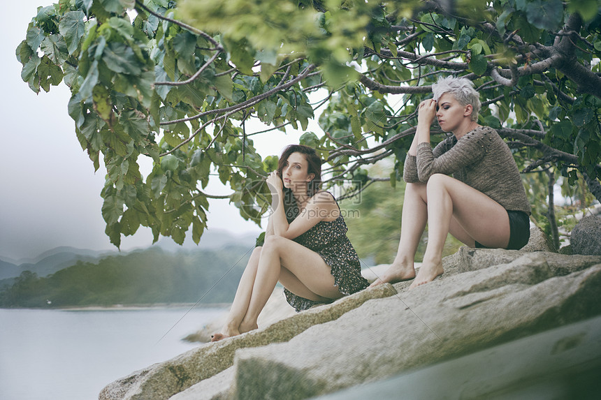 坐在港口岩石上的两个年轻女人图片