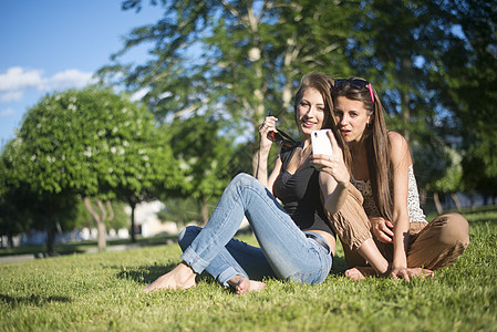 公园里的两位年轻女朋友用手机拍照图片