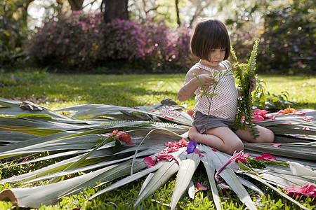 坐在花园叶子上插花的女童图片