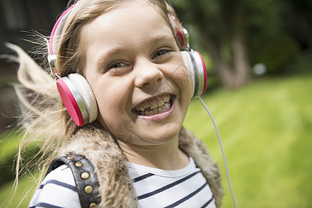 女孩在路上用耳机收听音乐图片