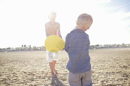 男孩和兄弟在海滩上打球图片