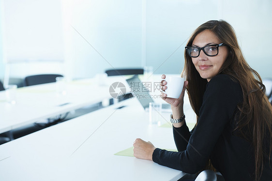 在会议桌上喝咖啡的女商人肖像图片